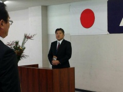 日本国旗が掲げられた壁の前に市長が立って訓示を行っている写真
