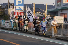 厄払いと書かれたのぼり旗を持ち仮装した人たちが縦一列に並んで歩道を歩いている様子の写真