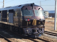 線路に停まっている紫色の電車の先頭車両を左斜め前から写している写真