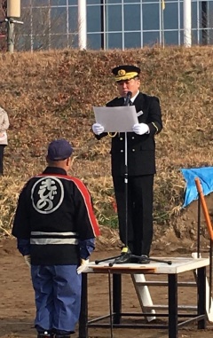 制服姿の市長が台の上に立ち、前に立っている消防団員の男性に紙を見ながら話をしている写真