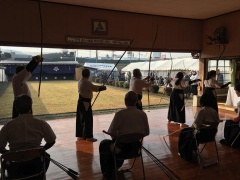 弓道場で袴を着た人たちが弓を持って弓道をしている様子を後ろから写している写真