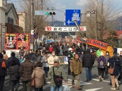 奥の頭上に京町二日市と幕がかかっていて、手前の道路に沢山の人が歩いている写真