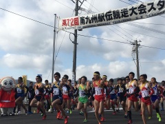 頭上に南九州駅伝競走大会と幕がかかったスタート地点からランナーが走り出している写真
