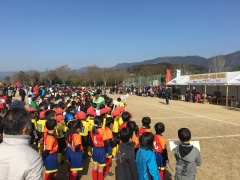 サッカーのユニフォーム姿の子供たちが整列してグラウンドに立っている写真