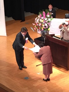 舞台上でえびの市長が向かい合った女性に賞状を渡している写真