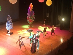 舞台上で、衣装を着た出演者が踊っている写真