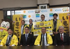 黄色い法被を着た市長や関係者が、マスコットキャラクターむぅちゃんや河野知事と並んでいる記念写真