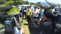 報道カメラマンが、磯崎農林水産副大臣と河野知事と市長が話をしている様子を撮影している写真