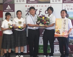 花を持っている男女の学生と市長、パンフレットを持っている男性の写真