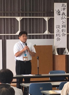 島津義弘公顕彰会設立総会と書かれた弾幕の前でマイクをもって立っている市長の写真