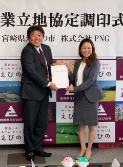 株式会社PNGの関係者の女性と市長が笑顔で協定書を持っている写真