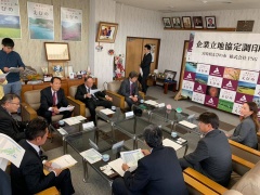 市長、株式会社PNGの関係者達が座って資料を見ながら話をしている写真