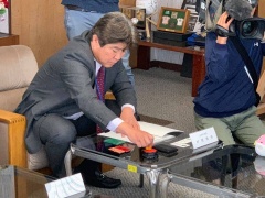 市長がテーブルに置かれている資料に押印しようと印鑑に朱肉をつけている写真