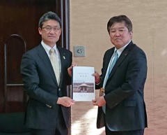 宮崎県知事と市長が、両手で書類を一緒に持っている写真