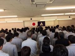 日本国旗とえびの市章の前に立っている市長の話を聞いている市役所職員の写真