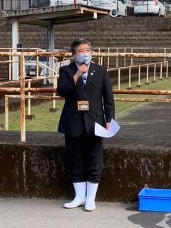 白い雨靴を履いた市長が、マイクを持って話をしている写真