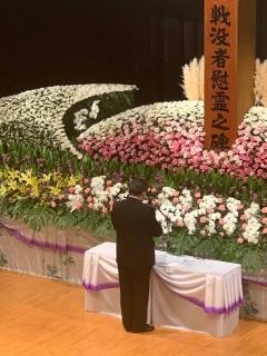 戦没者追悼式で、花壇の前に立つ男性の後ろ姿の写真