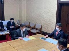 市長、宮崎県知事が資料の置かれた机に座って話をしている写真