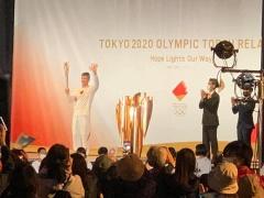 井上康生さんが、舞台上でトーチを持ち、左手を振っている写真