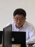 黒色のノートパソコンを見ているメガネをかけた市長の写真