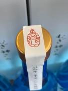 青色の瓶のキャップ部分にキャラクターの印が押されている白いテープが貼ってある写真