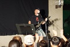 泉谷しげるさんが、ギターを弾きながら歌っている、その様子を見ている観客の後頭部が写っている写真