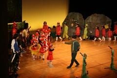 舞台上で赤い衣装を着た子供たちが円を作るように並んで歩いている写真