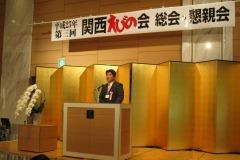 関西えびの会総会・懇親会で壇上で話をしている男性の写真