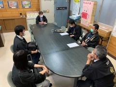市長や黒い法被を着た関係者が木製机の席に間隔をとって座り、話をしている写真