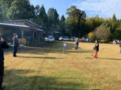 芝生のグラウンド内でマスクをした市長と、グランドゴルフのクラブを持った選手が距離を取りながら向かい合っている写真