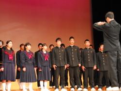 制服を着た中学生が舞台上に並び、合唱をしている写真