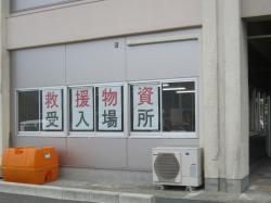 救援物資受入場所と書かれた紙が貼られた建物の窓の写真