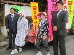 衣装を着て、顔におしろいを塗り、化粧をしている2人の祭り参加者と、市長と男性が並んでいる写真