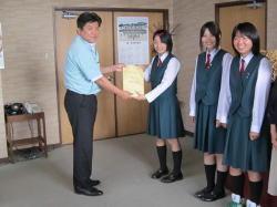 3名の制服を着た女子生徒の1人から封筒を受け取る市長の写真
