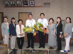 えびの市地域婦人連絡協議会の6名の女性とひまわりの花束も持つ市長と男性の記念写真