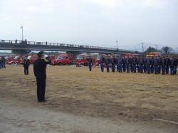 湯田橋下流河川敷で、制服を着た消防団が整列している写真