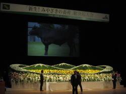 花祭壇の後ろのスクリーンに牛の写真が映しだされている写真
