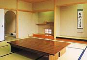 落ち着いた佇まいの和室の真ん中に大きな木のテーブルが置かれた部屋内部を写した写真